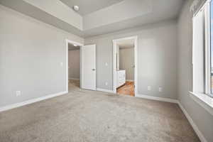 Unfurnished bedroom with light carpet and ensuite bath