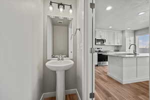 Bathroom with sink, wood-type flooring, and a textured ceiling