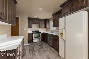 Kitchen with sink, stainless steel appliances, dark brown cabinets, and light wood-type flooring