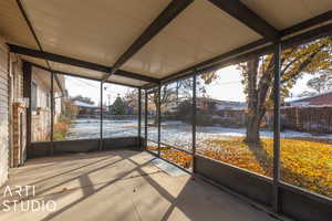 Unfurnished sunroom featuring beamed ceiling and a healthy amount of sunlight