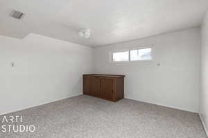 Carpeted empty room featuring a textured ceiling