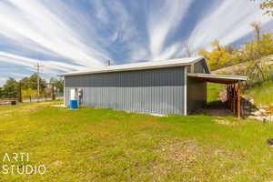 View of property exterior featuring a lawn and an outbuilding