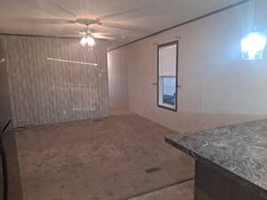 Interior space with carpet flooring, ceiling fan, and wooden walls