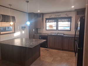 Kitchen featuring black appliances, dark brown cabinets, pendant lighting, and sink