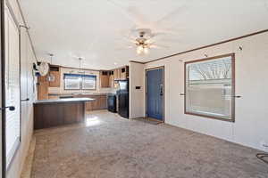 Kitchen with ceiling fan, black appliances, light carpet, decorative light fixtures, and kitchen peninsula