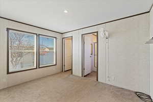 Unfurnished bedroom featuring light carpet and crown molding