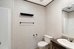 Bathroom with vanity, ornamental molding, and toilet