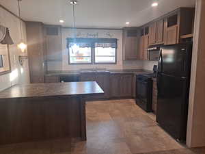 Kitchen featuring black appliances, sink, hanging light fixtures, tasteful backsplash, and dark brown cabinets