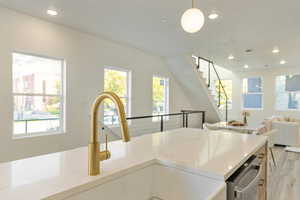 Kitchen featuring dishwasher, light wood-type flooring, hanging light fixtures, and sink