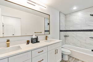 Full bathroom featuring tiled shower / bath, vanity, toilet, and wood-type flooring