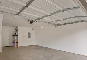 Garage featuring electric panel, strapped water heater, and a garage door opener