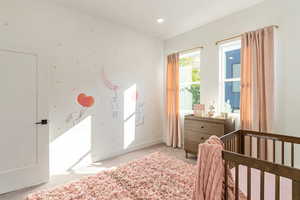 Bedroom featuring light colored carpet and a nursery area