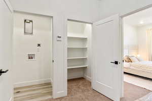 Interior space featuring electric dryer hookup, hookup for a washing machine, and light colored carpet