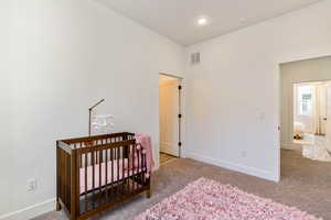 Bedroom featuring a crib and carpet floors