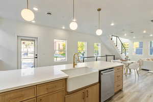 Kitchen with pendant lighting, dishwasher, sink, and light hardwood / wood-style flooring