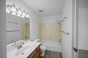 Full bathroom with wood-type flooring, vanity, bathing tub / shower combination, and toilet