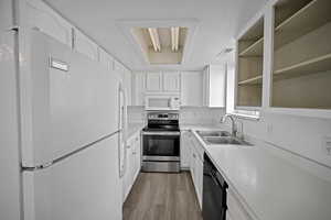 Kitchen featuring white cabinetry, light wood-type flooring, white appliances, and sink