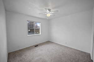 Spare room featuring ceiling fan, carpet, and a textured ceiling