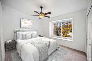 Carpeted bedroom with ceiling fan and a closet