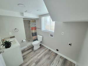 Bathroom with walk in shower, a textured ceiling, toilet, vanity, and hardwood / wood-style flooring