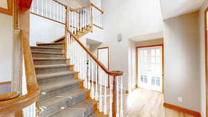 Staircase with wood-type flooring and a high ceiling