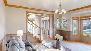 Living room featuring ornamental molding, light hardwood / wood-style floors, and an inviting chandelier