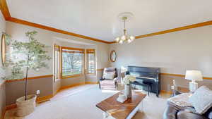 Living room with crown molding, light hardwood / wood-style flooring, and an inviting chandelier