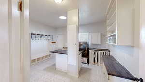 Interior space with butcher block countertops, white cabinets, a textured ceiling, and washer / dryer