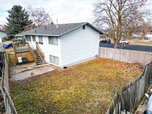 Rear view of house featuring a lawn and a deck