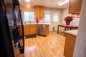 Kitchen featuring dishwasher, black refrigerator, sink, and light hardwood / wood-style flooring