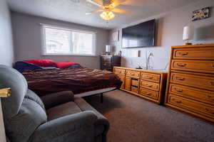 Bedroom featuring carpet flooring, ceiling fan, and a textured ceiling