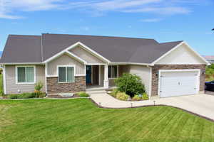 View of front of property with a porch, a garage, and a front lawn