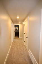 Corridor with sink and light colored carpet