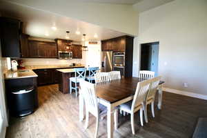 Dining area with light wood-type flooring, high vaulted ceiling, and sink