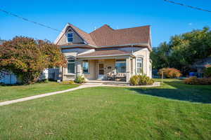 Rear view of house with a porch and a yard