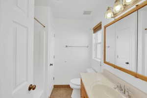 Bathroom with tile patterned floors, vanity, and toilet off of primary bedroom