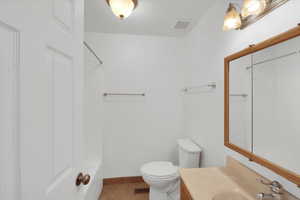 Full bathroom featuring toilet, vanity, tile patterned floors, and washtub / shower combination