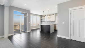 Kitchen featuring white cabinets, a kitchen island, hanging light fixtures, and a healthy amount of sunlight