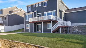 Back of house with a lawn and a deck