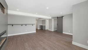 Unfurnished living room featuring a barn door and dark hardwood / wood-style floors