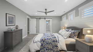 Carpeted bedroom with a barn door and ceiling fan