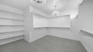 Spacious closet with light colored carpet and an inviting chandelier