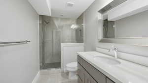 Bathroom with tile patterned flooring, a shower with door, vanity, and toilet