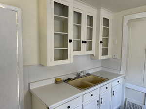 Kitchen featuring white cabinetry and sink