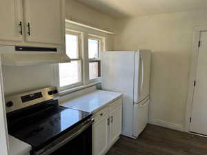 Kitchen featuring white cabinets, dark hardwood / wood-style floors, stainless steel electric stove, and white fridge