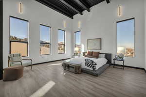 Bedroom featuring beam ceiling, light hardwood / wood-style flooring, high vaulted ceiling, and wooden ceiling