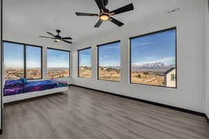 Bedroom with ceiling fan, a mountain view, and light wood-type flooring