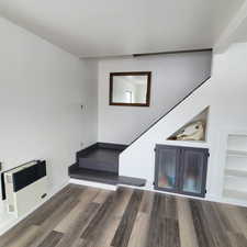 Interior space with wood-type flooring, heating unit, and built in shelves