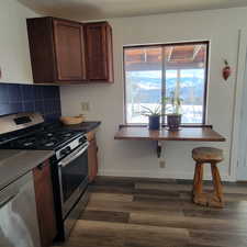 Kitchen featuring dishwashing machine, dark hardwood / wood-style flooring, tasteful backsplash, and stainless steel gas range