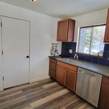 Kitchen featuring decorative backsplash, dishwasher, sink, and dark hardwood / wood-style flooring